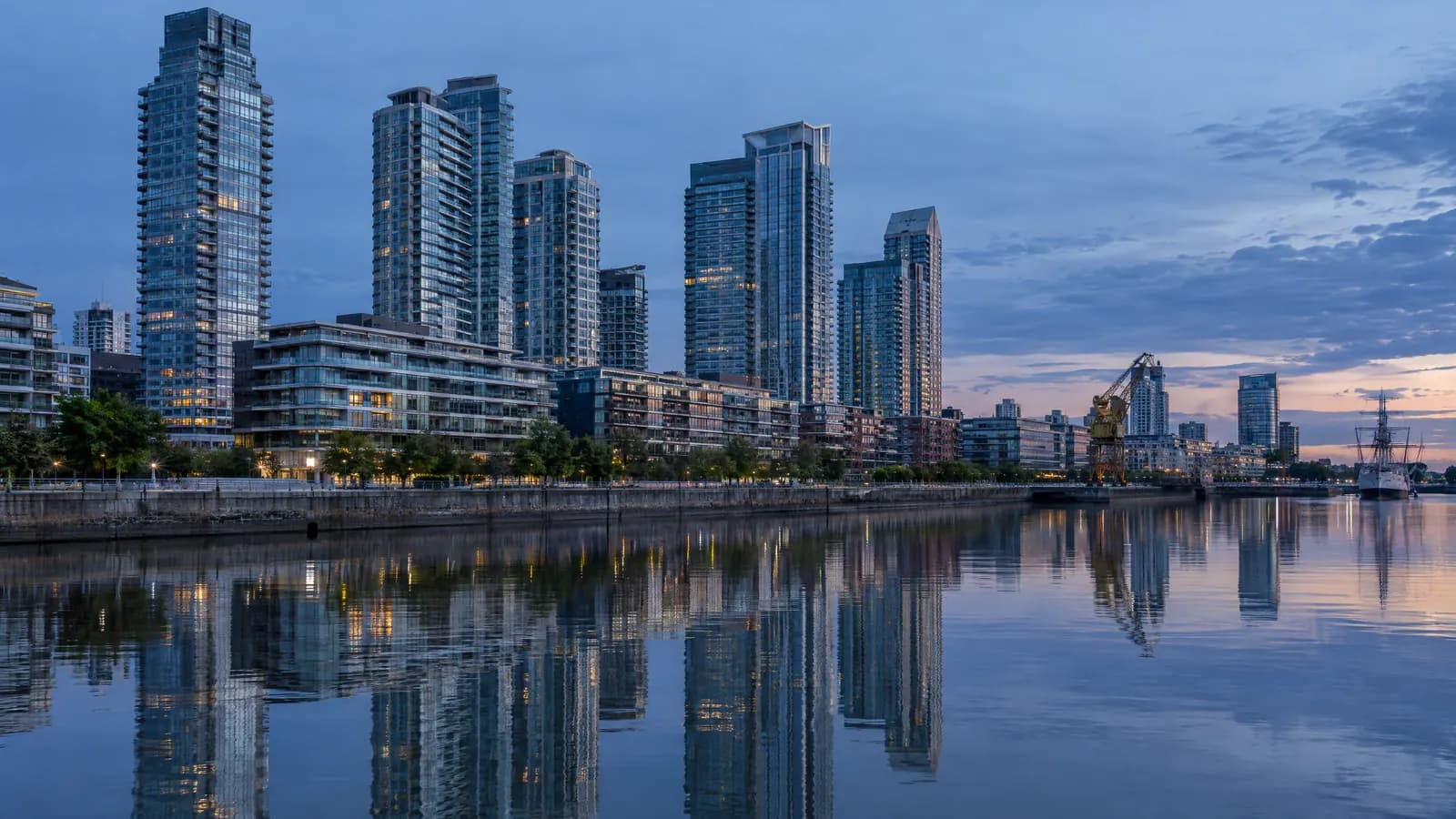 Torres residenciales de vidrio de Puerto Madero reflejadas en el agua del dique al anochecer.